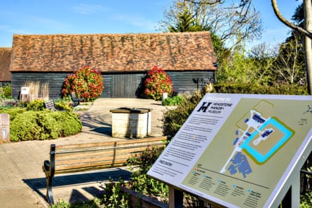 A garden with an information board for Headstone Manor Museum and a low building with black weatherboards and red tile roof