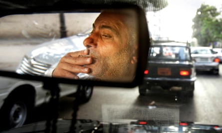 A taxi driver smokes a cigarette while driving his cab in downtown Cairo, Egypt, on 6 July 2014.