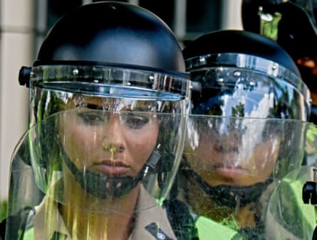 Police officers stand guard as university students stage an anti-government protest.