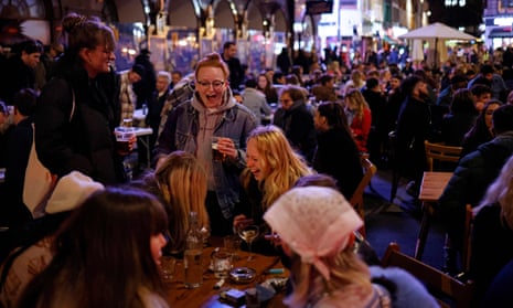 Customers enjoy drinks at tables outside the pubs and bars in Soho, central London