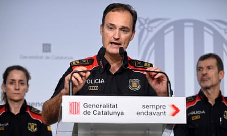 Eduard Sallent speaks into a microphone at a podium, flanked by two Mossos d’Esquadra officers