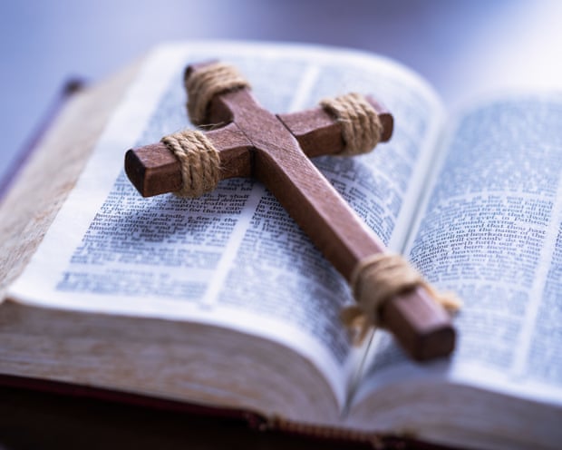 A cross is placed on an open page of the Bible