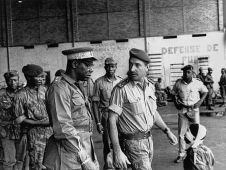 Black and white photograph of two military officers, one black, one white, walking together in a barracks