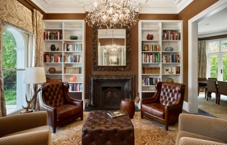 A fancy-looking living room with a fire place and multiple book shelves