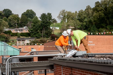 Anthony Hamilton, left, and Mason Taylor, right, work for Secure Futures installing solar panels on the roof of St Paul elementary school in St Paul, Virginia, on 31 August.