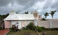 Man works on pink and cream house as hurricane approaches