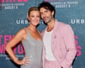 Woman and man smile on red carpet with arms around each other