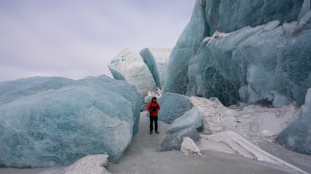 A member of the expedition team dwarfed by an Arctic glacier.