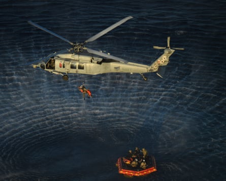 A NASA Artemis II crew member being hoisted into a US Navy MH-60 helicopter after successfully splashing down in the Pacific Ocean.