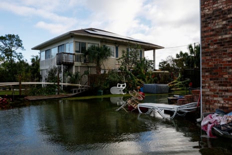 flood water outside of home next to outdoor furniture and belongings