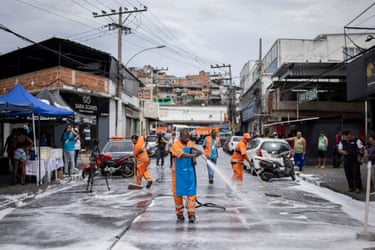 Municipal workers in orange overalls wash away blood in São Lucas Square