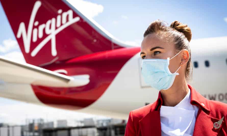 Masked cabin crew by a Virgin plane