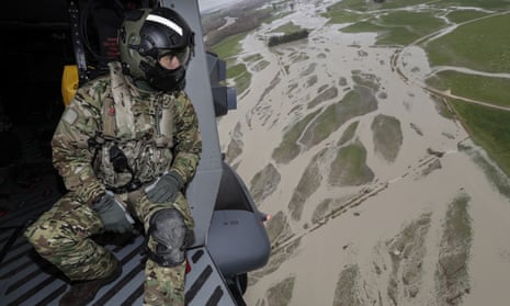 A New Zealand air force helicopter crewman looks down at flood-affected areas south of Christchurch, New Zealand