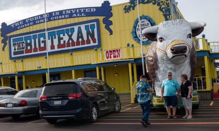 Tourists pose in front of the oversized cow statue at The Big Texan restaurant.