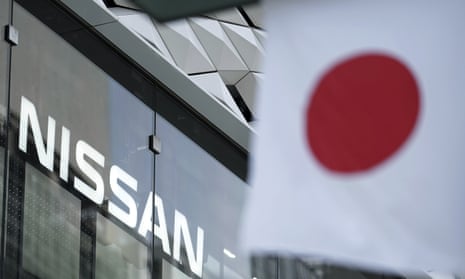 Nissan logo is seen near a Japanese flag at the automaker’s showroom