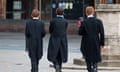 Three boys in Eton college uniforms walk away from the camera