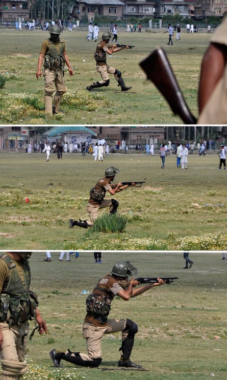 An Indian policeman aims a pellet gun towards Kashmiri protesters in Srinagar in July.