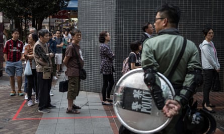 Police watch as people queue in front of a polling station in Hong Kong