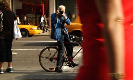Bill Cunningham shooting on the street in New York in his trademark blue janitor’s jacket.