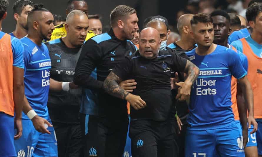 Marseille manager Jorge Sampaoli is led away from the chaos.