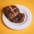 A Waitrose milk chocolate & fudge hot cross bun, sliced, toasted and buttered, on a white plate