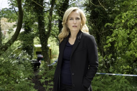 Gillian Anderson wearing a black coat and standing among trees with police tape behind her, playing a police officer in TV drama The Fall