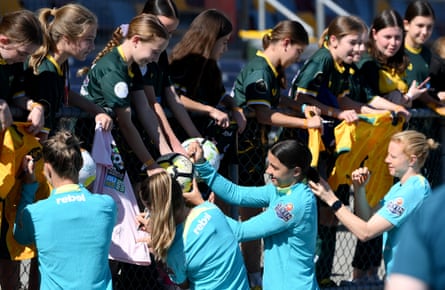 Players sign autographs for young fans from the Mt Gravatt Hawks Football Club during a Matildas open training session in Brisbane