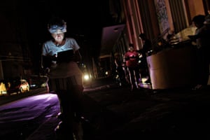 A woman uses her tablet at night in one of the few places with signal access in San Juan. A 7pm-6am curfew has been imposed