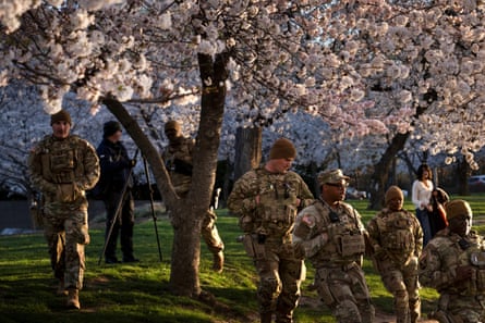 Members of the National Guard walk under cherry blossoms.