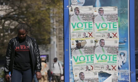 A woman walks past images of the party leader Emmerson Mnangagwa pasted on a board in Harare, Zimbabwe, 18 August 2023.