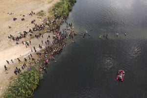 A Mexican rescue boat chugs along the river as people wade across