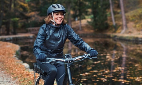 A senior woman with e-bike cycling outdoors on a road in park in autumn