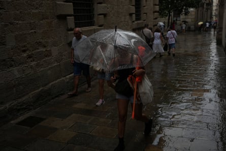 A woman holds an umbrella to protect herself from the rain as she walks around the Gothic Quarter in Barcelona, Spain.