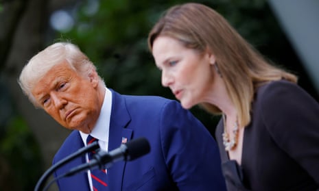 Donald Trump watches Amy Coney Barrett deliver remarks at the White House in Washington.