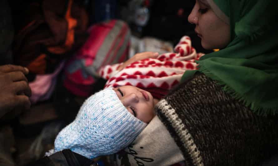 A woman holds a child as refugees take shelter in the village of Berkasovo