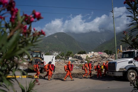 Members of the UK rescue team arrive at a collapsed building carrying their kit
