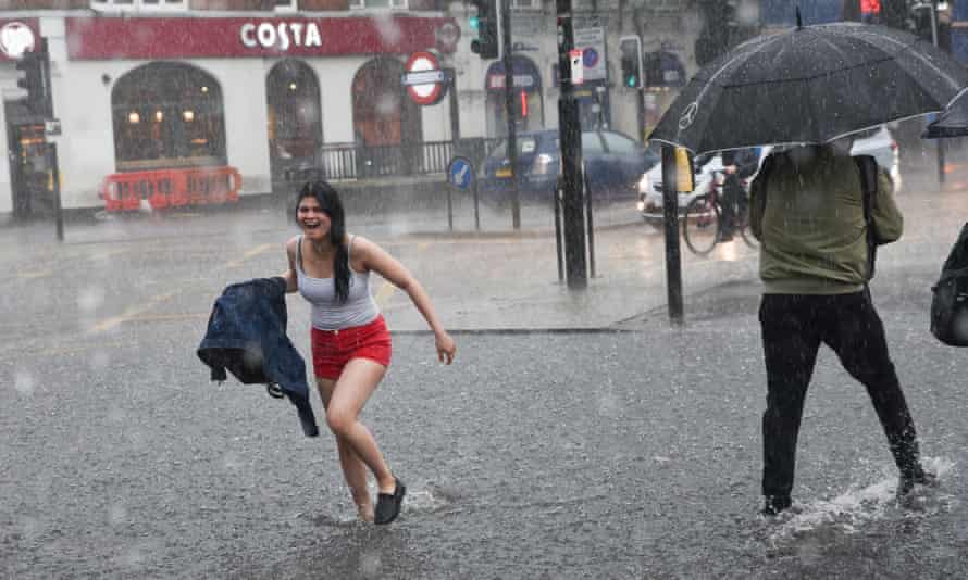 Gente hasta los tobillos en el agua en una calle de la ciudad mientras la lluvia cae