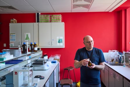 Um homem está em um laboratório segurando um frasco de amostra.