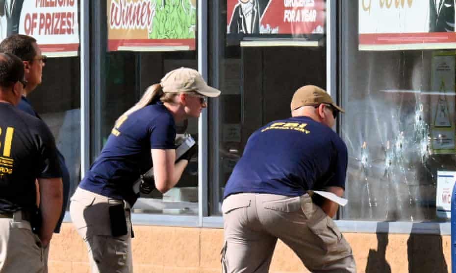 FBI agents look at bullet impacts in a Tops grocery store window in Buffalo, New York, on 15 May, the day after a gunman shot dead 10 people