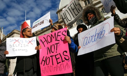 people hold signs condemning airbnb, including one saying 'homes not hotels'