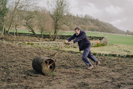 A man pushing a roller to flatten soil