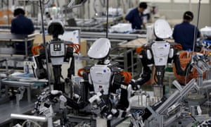 Humanoid robots work side by side with employees in the assembly line at a factory in Kazo, Japan.