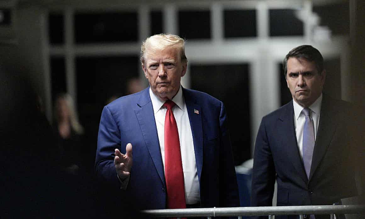Donald Trump, in a blue suit and red tie, enters Manhattan criminal court.