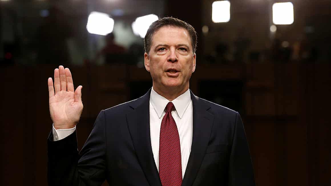 James Comey with hand up.
