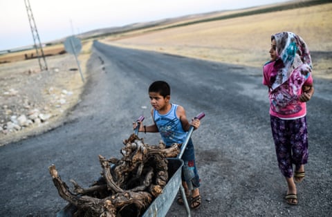 A young boy pushes a wheelbarrow full of wood on the outskirts of the Turkish-Syrian border town.