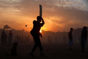 Peshawar. A boy is silhouetted against the setting sun as he plays cricket.