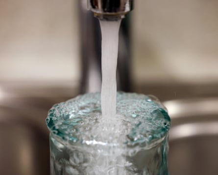 A close-up of a glass overflowing as as it is filled up with water from a tap