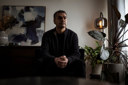 Saeid Zand seated on a couch in a living room with abstract art and indoor plants in the background