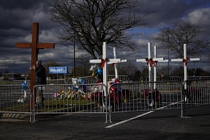 Dan Beazley supports a large wooden cross that he brought from his home in Detroit at a makeshift memorial in the parking lot of a Walmart in Chesapeake, US, for the six people killed there in a shooting
