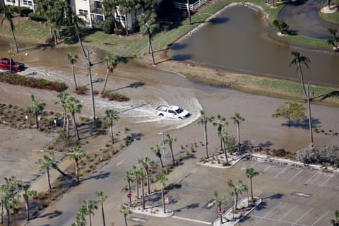 aerial view of white car driving through flooded street